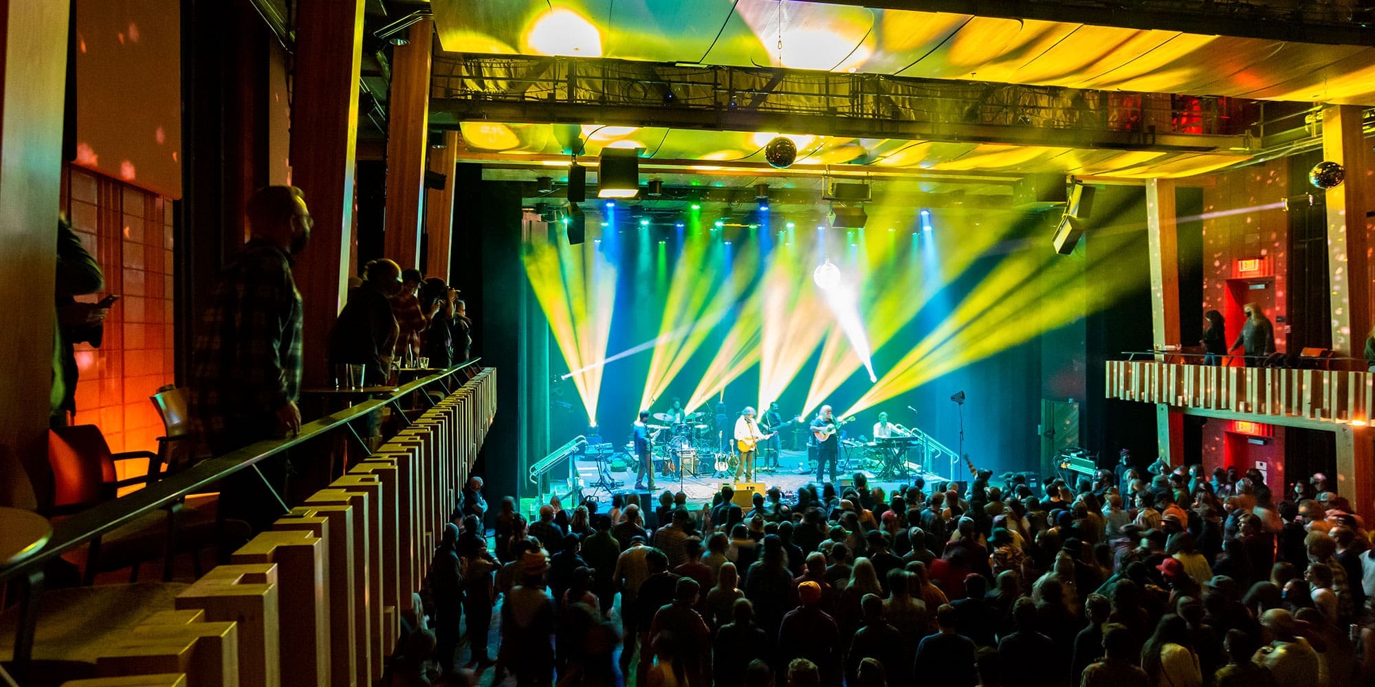 Large indoor concert with bright lights and a large crowd